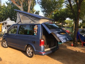 Blue VW T6 California Ocean campervan with pop-top roof raised at a campsite
